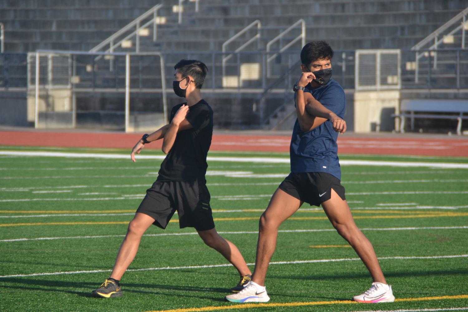 Jared Ho (11) and Nathaniel Lara (12) stretch after their warm up lap. Photo by Matthew Flores