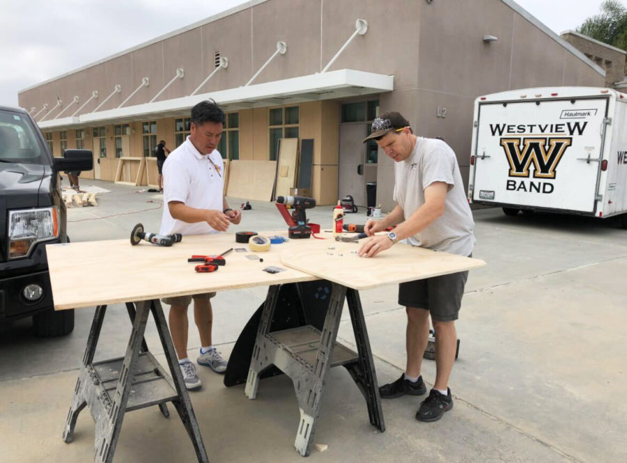 Chris Shaw (right) works with Rudy Del Rosario to improve the timpani cart for the percussion pit during marching band season, 2018. Band Dads work behind the scenes to design and create sets, as well as fixing and transporting them to and from band competitions.