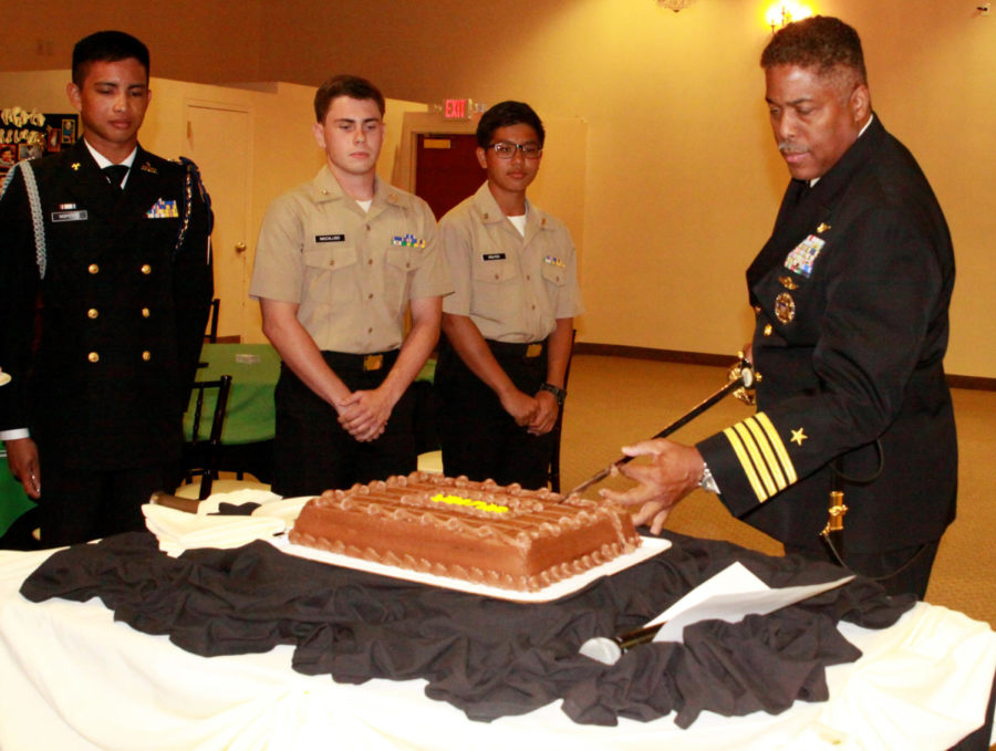 Nathan Nisperos (12), Kyle Macaluso (12), and Cory Nguyen (9) stand by as NJROTC supervisor Captain Thomas Adams slices the cake with a sharp saber. Following NJROTC tradition, Nguyen and Macaluso were the first to receive their slice of cake as the youngest and oldest cadets, respectively.