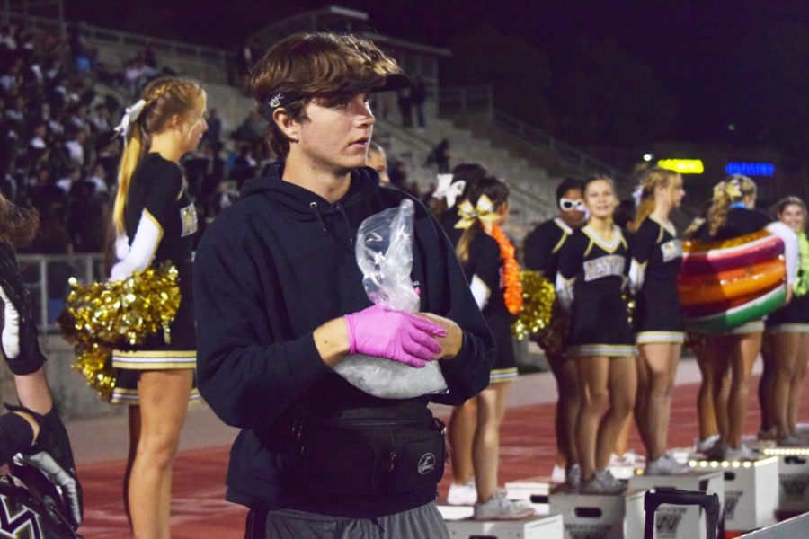 Larson Smith (11) prepares an ice pack for Mason Walsh (10) at the football game against Rancho Bernardo, Sept. 30. In the last year, Smith earned his CRP-AED credentials to become an athletic student aide. Photo by Swasti Singhai.
