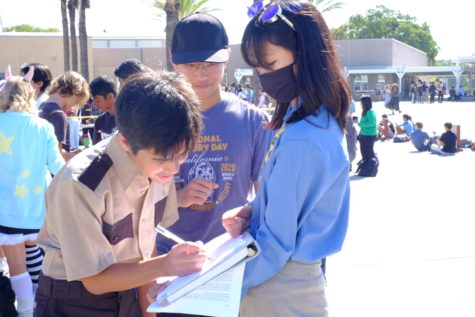 Augustin Goodman (9) signs petition presented by Phoebe Vo (10) and Daniel Tran (12), Oct. 28. The petition advocated for an increase in United States gun restrictions.