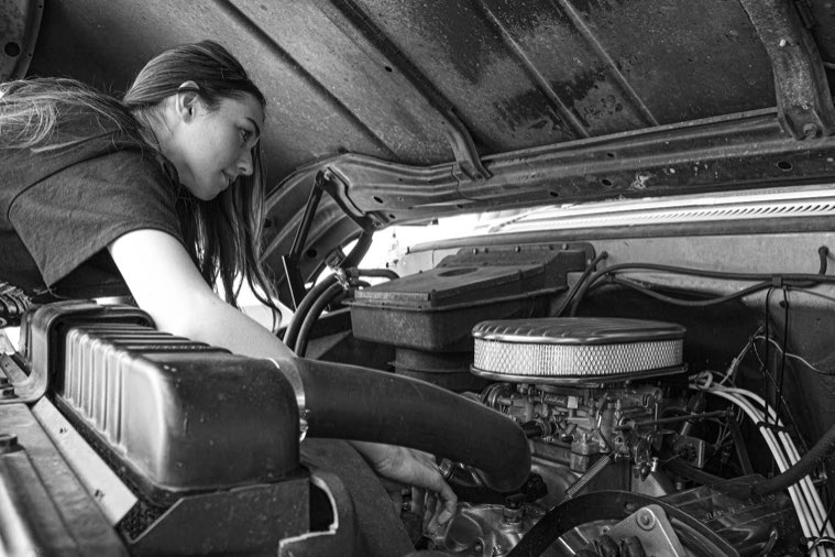 Daines adjusts the alternator and checks the carburetor in her 1966 Chevrolet C20 Custom Camper. Daines and her dad worked on repairing the truck for several years in Utah until they could tow it home. Now, Daines drives her truck every day to school. 