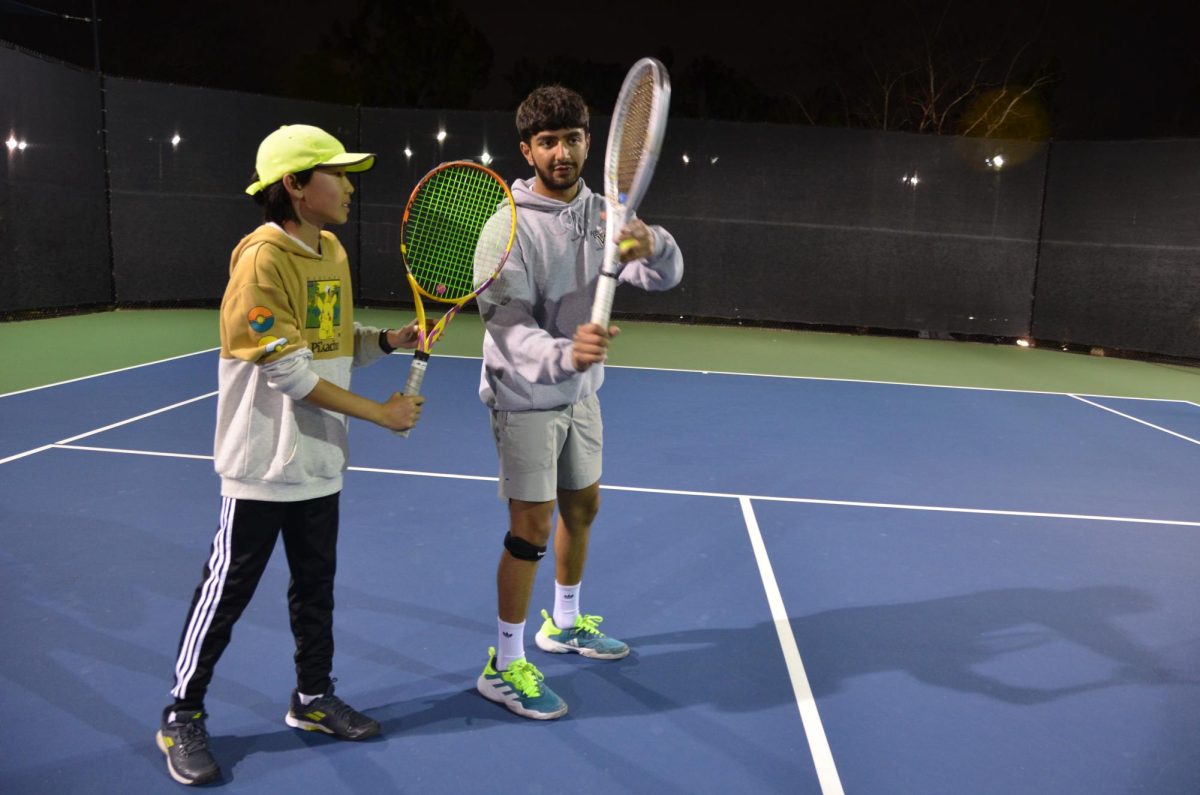 Atri Pandya (12) shows a novice tennis player proper backhand form. Pandya coaches privately and as a volunteer for Westview’s tennis clinics. 