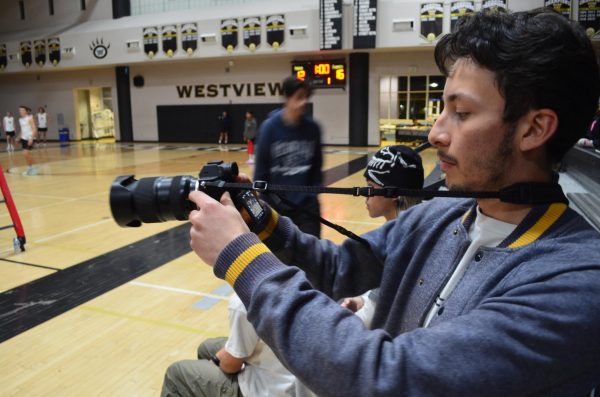Marko Huisa (12) takes pictures for the boys volleyball team during their match against Classical Academy, Feb. 29. Players also commission Huisa to film videos during the games and edit them together with music into highlight reels. 