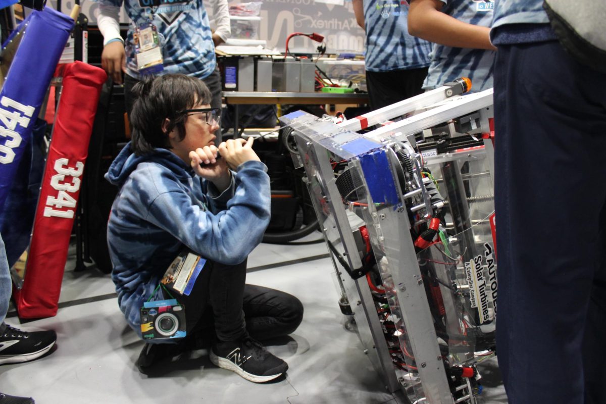 Jayden Chu (10) inspects the robot at FRC Regionals, March 23. During the match, the teams competed to shoot the most foam rings at a target. 