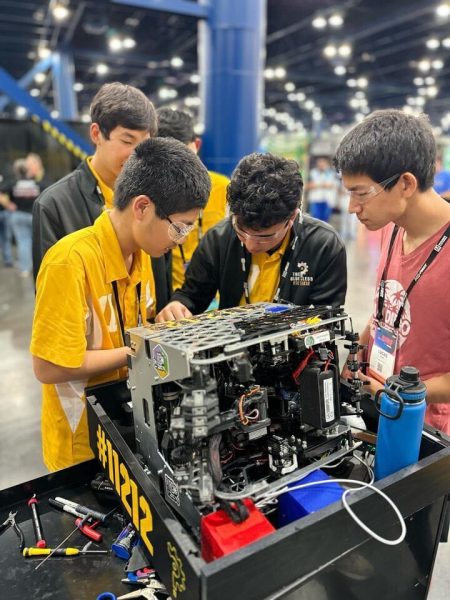 Members of The Clueless tighten the wheels on their robot after it took a hit at conference finals, April 20. The team beat 223 FTC teams from around the world to win. (Photo courtesy of Nathan Xie)