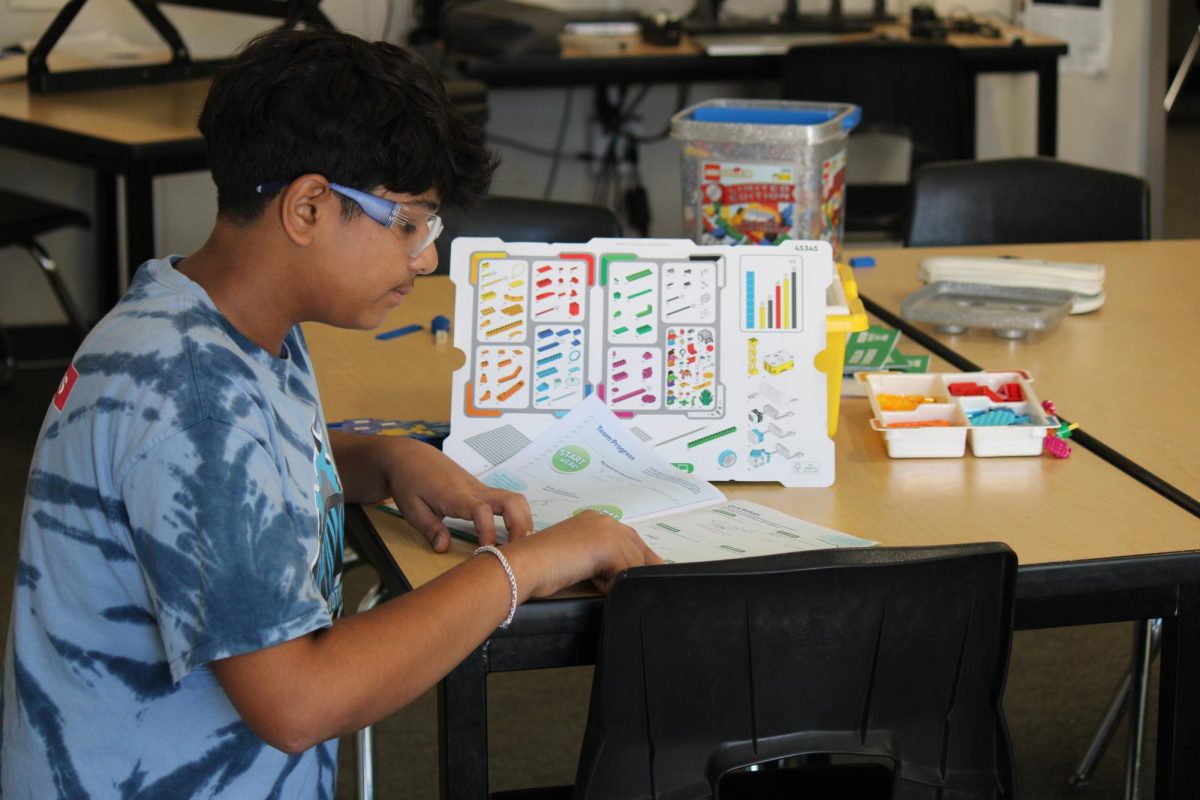 Sanchay Koppa (10) demonstrates how to build a Legos with the FIRST Lego League (FLL) Explore Engineering Notebook, Oct. 9, Koppa mentors elementary school students to prepare them for the engineering, design, and creativity required in robotics.