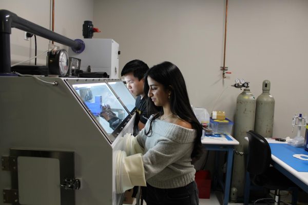 Shayna Mehta (12) [front] and Dylan Deng (12) [back] work in a glove box, filling cartridges with hydrogel, Monday. They both work at Solutions Matter. 