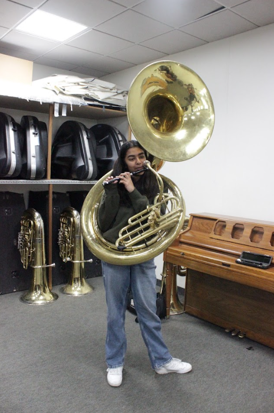 Maya Keyal (11) plays piccolo while carrying a tuba, Feb. 6. In band, she switches between playing the two. 