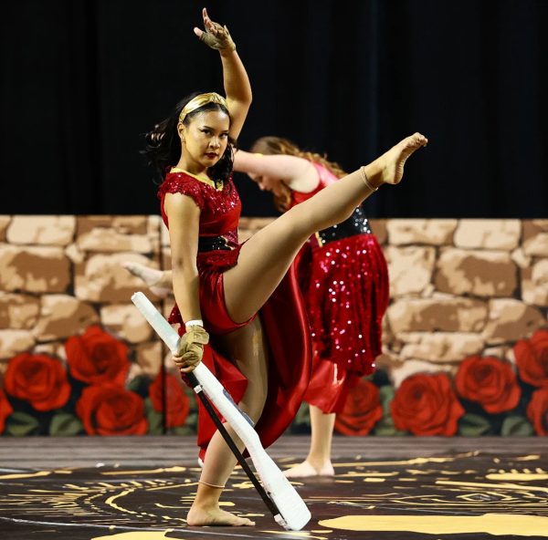Serenity Calica (12) fan kicks over her rifle at the 2025 Winter Guard Association of Southern California competition, April 13. Color Guard's performance theme this year was based on tarot cards. 