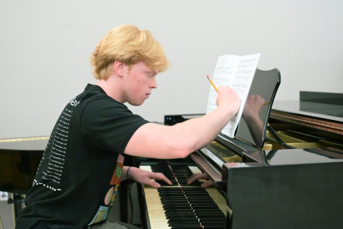 Luke Millay (12) writes notes on his sheet music with his right hand as he plays melodies with his left, Oct. 2. He has been composing classical music since the seventh grade.