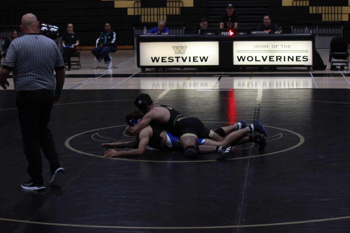 Gabriel Rubin (12) wraps his arm around his opponent's neck while pinning him to the floor, performing a 'cross-face' maneuver in his Senior Night wrestling match against San Pasqual, Jan. 29. Despite a strong individual performance from Rubin, the team lost 53-26 to end the regular season.