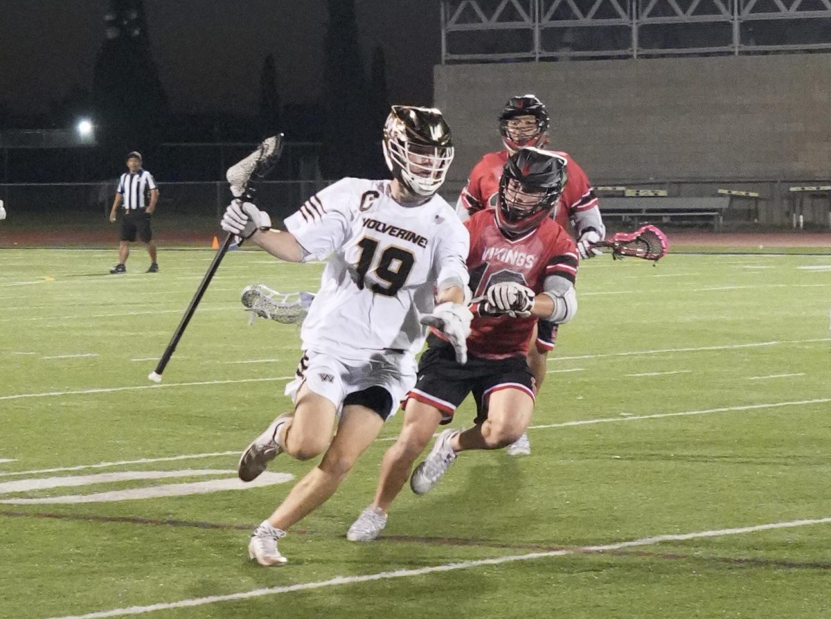 Midfielder Michael Brownlee (11) dodges opponent’s attempt to check, March 20. Boys lacrosse held a lead throughout the entire game, defeating La Jolla High, 11-4.