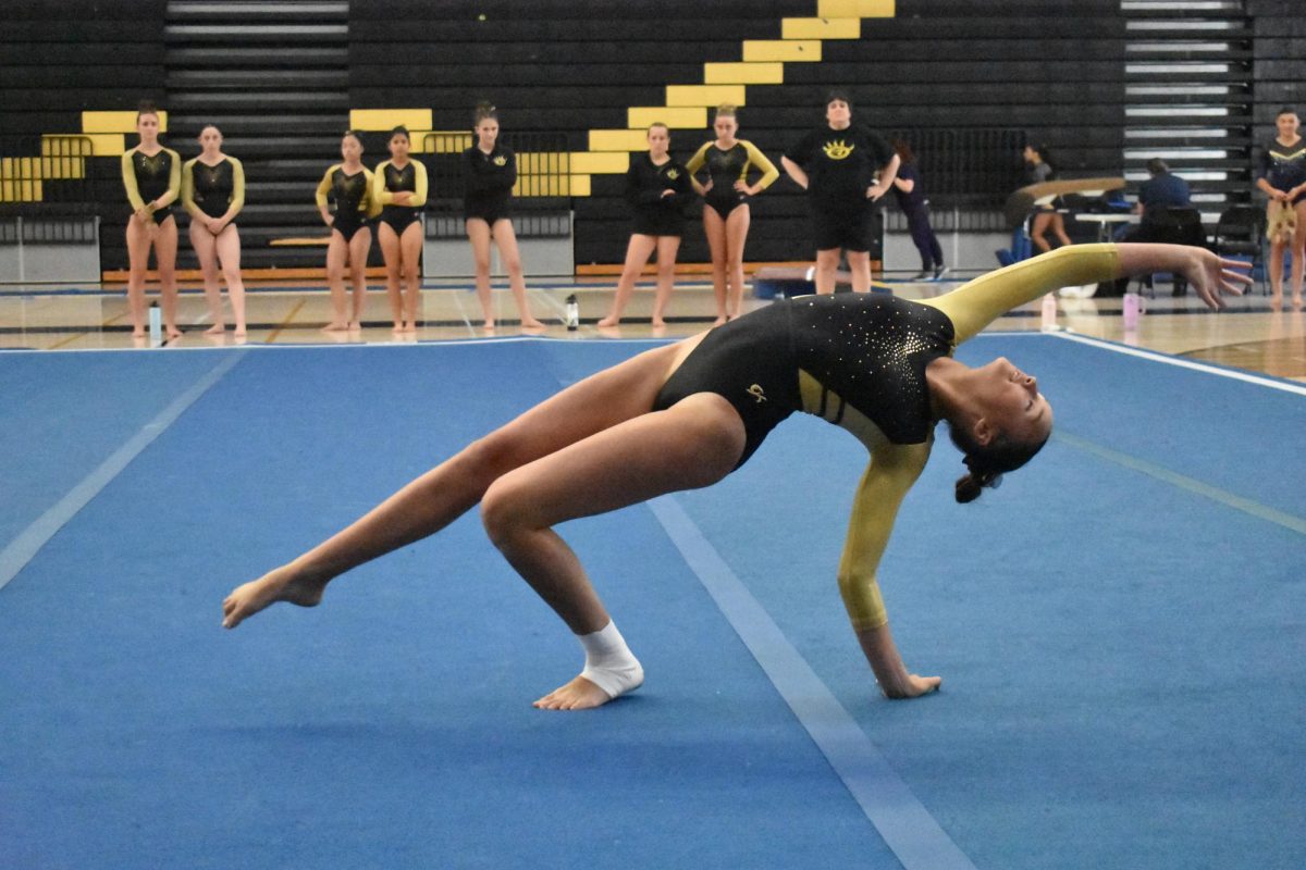 Veronika Calimlim(9) pushes up into a back walkover during her floor routine, April 16. Gymnastics won the all-around title for both the compulsory and optional categories.